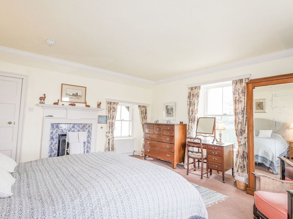 A bedroom with a bed, chest of drawers, and a mirror at Druidaig Lodge in Kyle