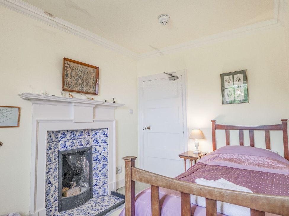 A bedroom with a bed, lamp, and fireplace at Druidaig Lodge in Kyle