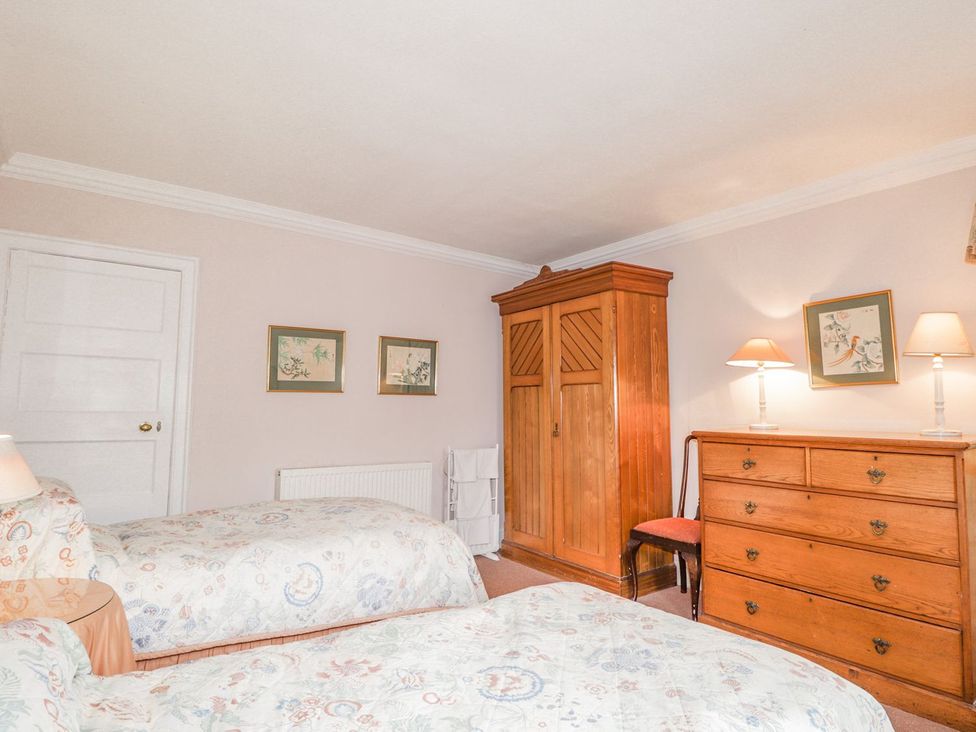 A bedroom with two beds, a wardrobe, and a dresser at Druidaig Lodge in Kyle