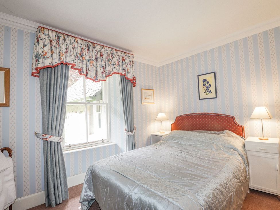 A bedroom with a bed, nightstands and curtains at Druidaig Lodge in Kyle