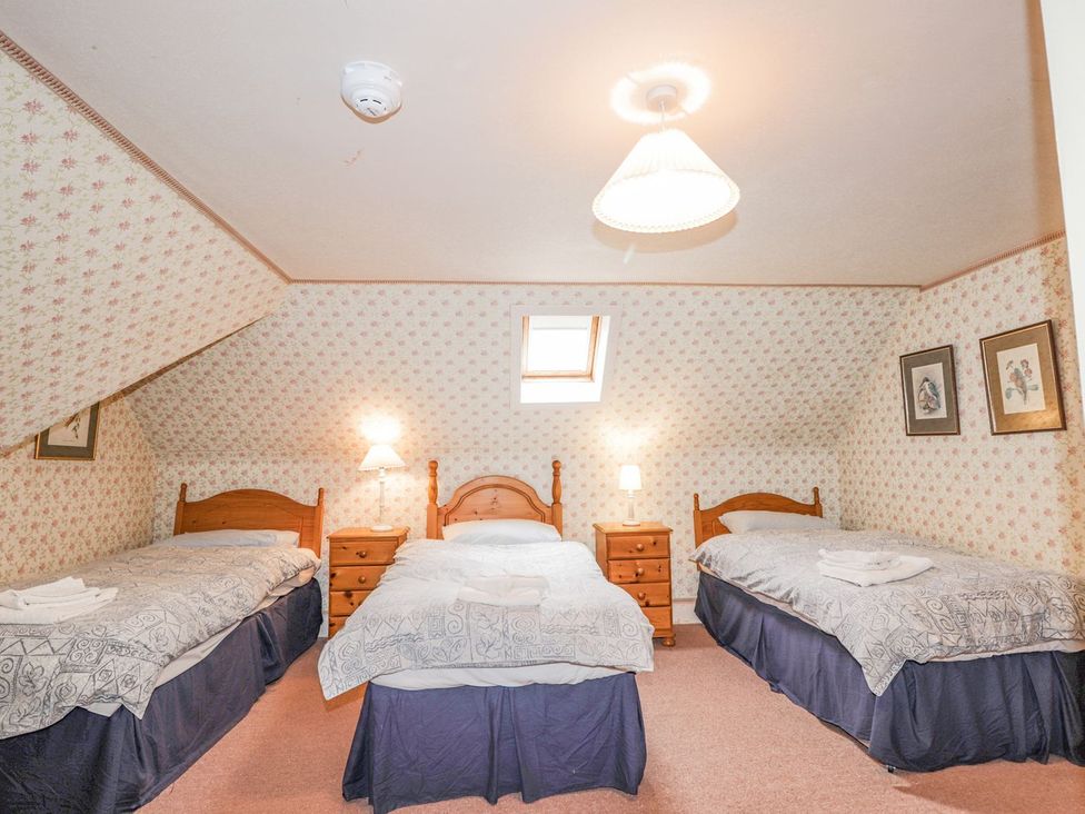 A bedroom with three beds and a nightstand at Druidaig Lodge in Kyle