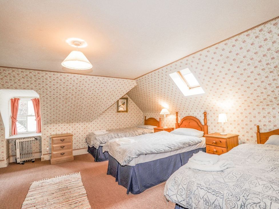 A bedroom with three beds and a window at Druidaig Lodge in Kyle