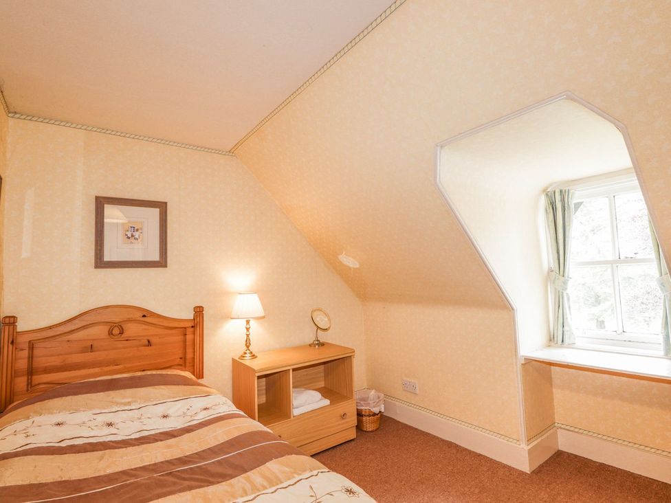 A bedroom with a bed, lamp, and table at Druidaig Lodge in Kyle