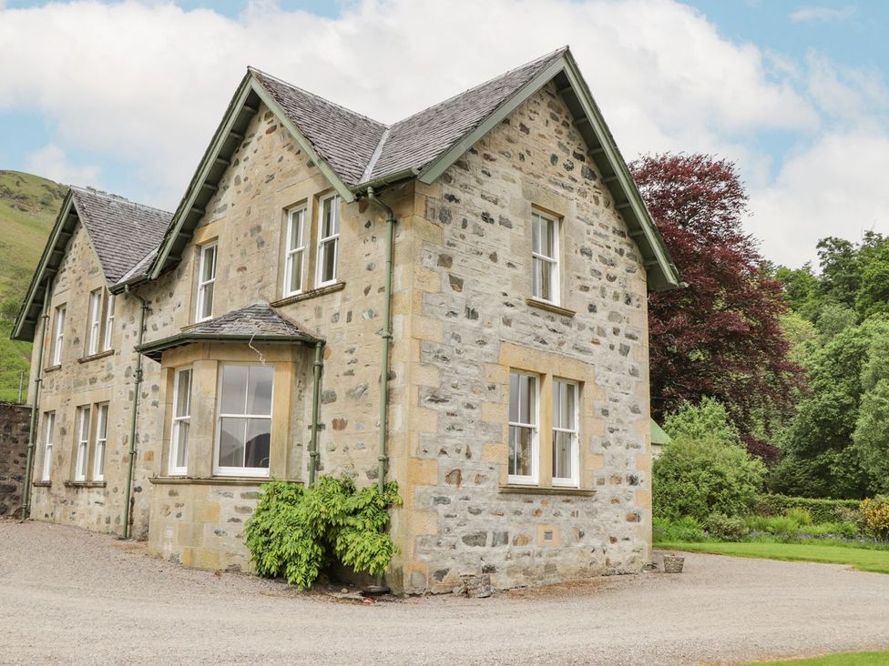 A stone building with windows and a garden at Druidaig Lodge in Kyle
