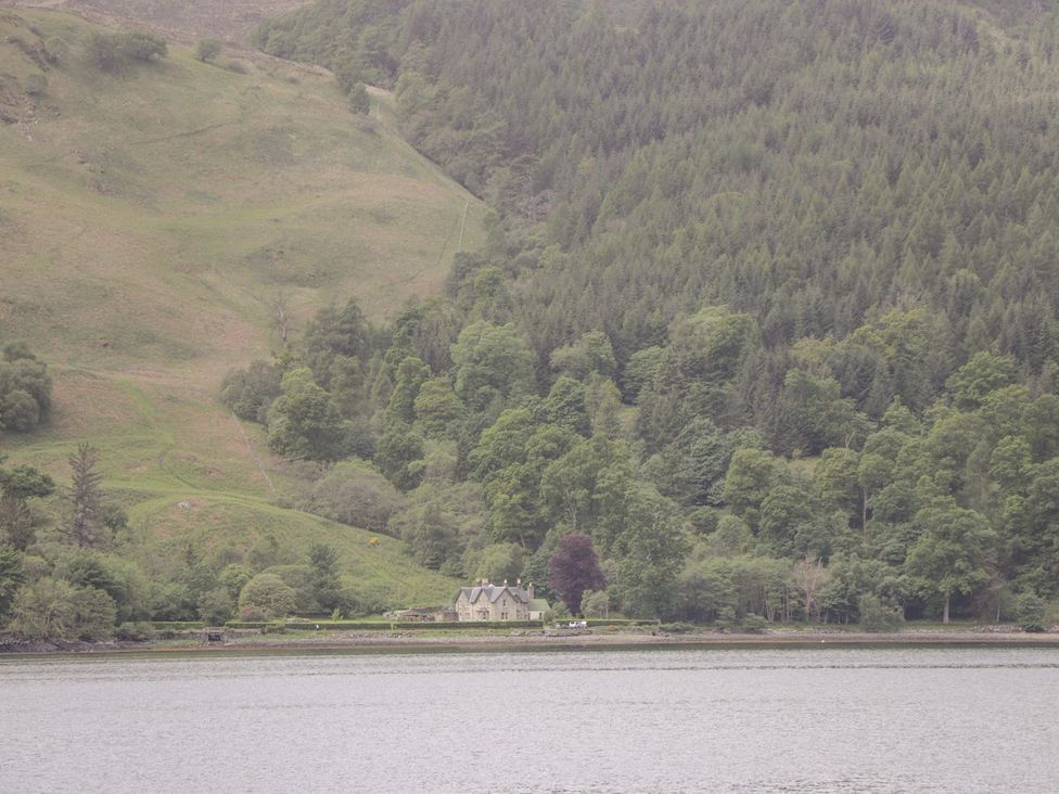 A house surrounded by trees and hills near the water at Druidaig Lodge in Kyle