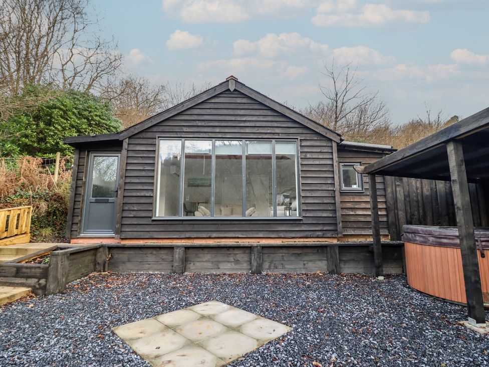 A wooden cabin with large windows and a hot tub at Lodge at Nadur