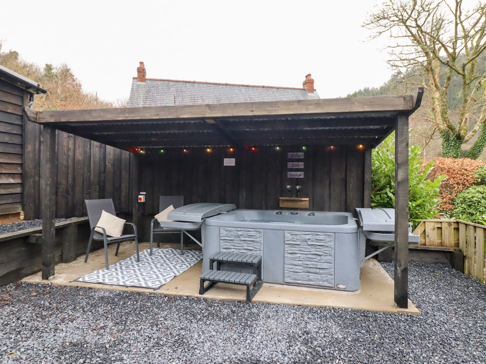 An outdoor area with a hot tub and chairs at Lodge at Nadur Commins Coch near Machynlleth