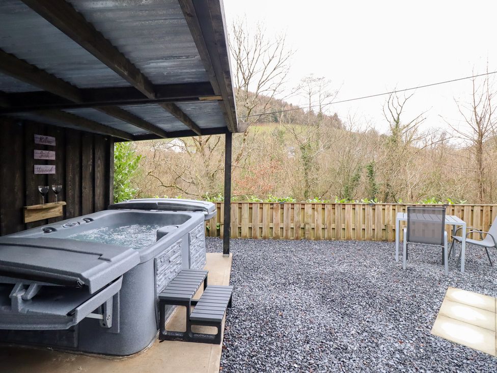 An outdoor area with a hot tub and seating at Lodge at Nadur Commins Coch near Machynlleth