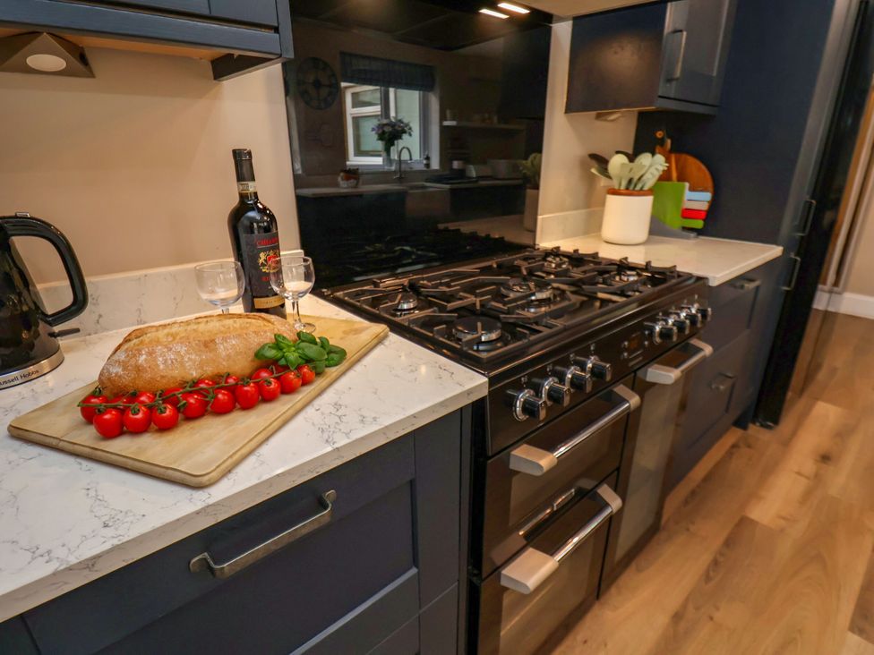 A kitchen with a stove and cutting board with bread and tomatoes at Sunnyvale House in Whitby