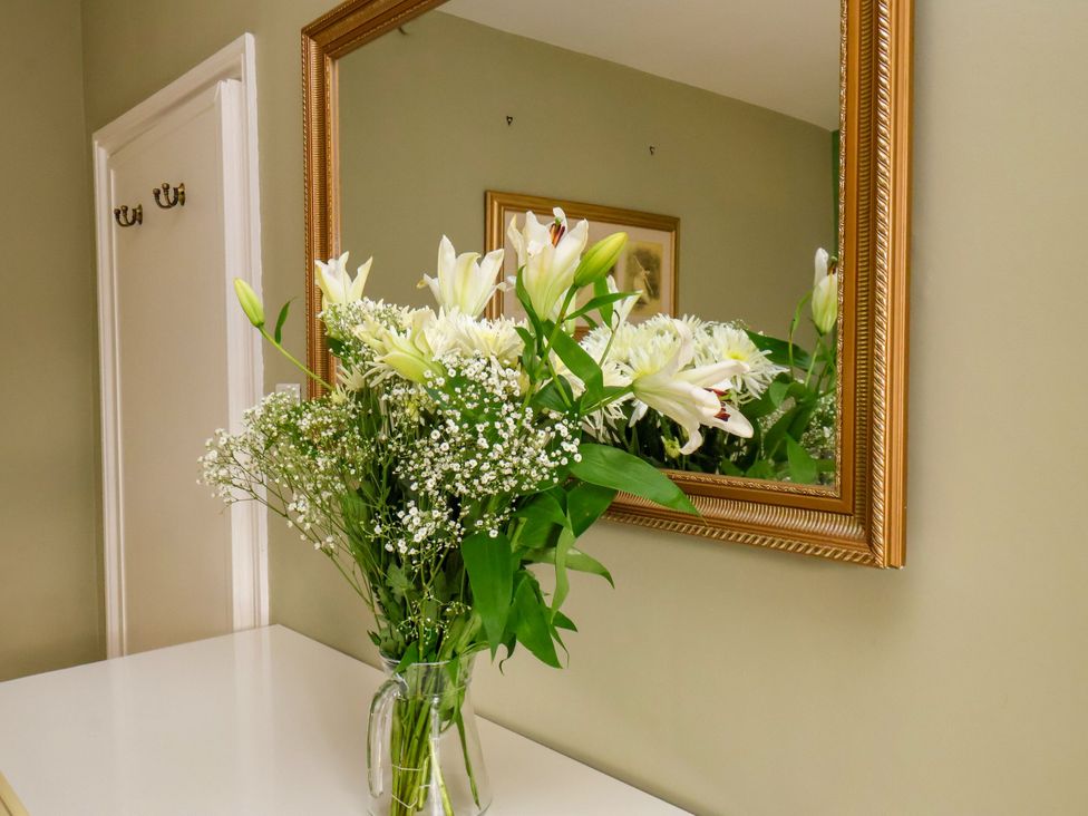 A vase of flowers on a table next to a mirror at Sunnyvale House in Whitby