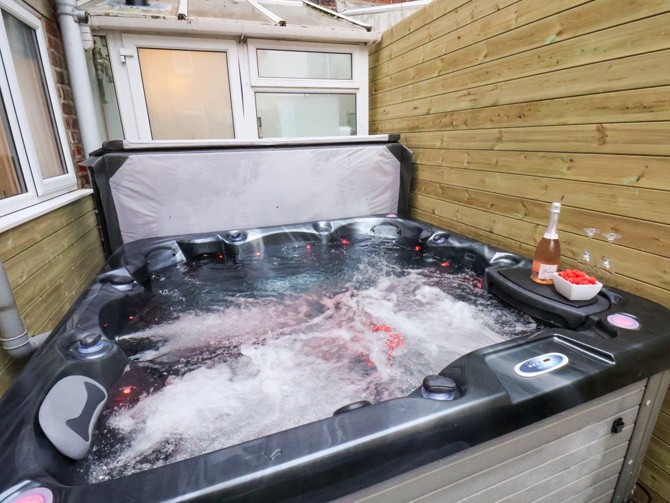 A hot tub with a bottle of champagne in an outdoor area at Sunnyvale House in Whitby