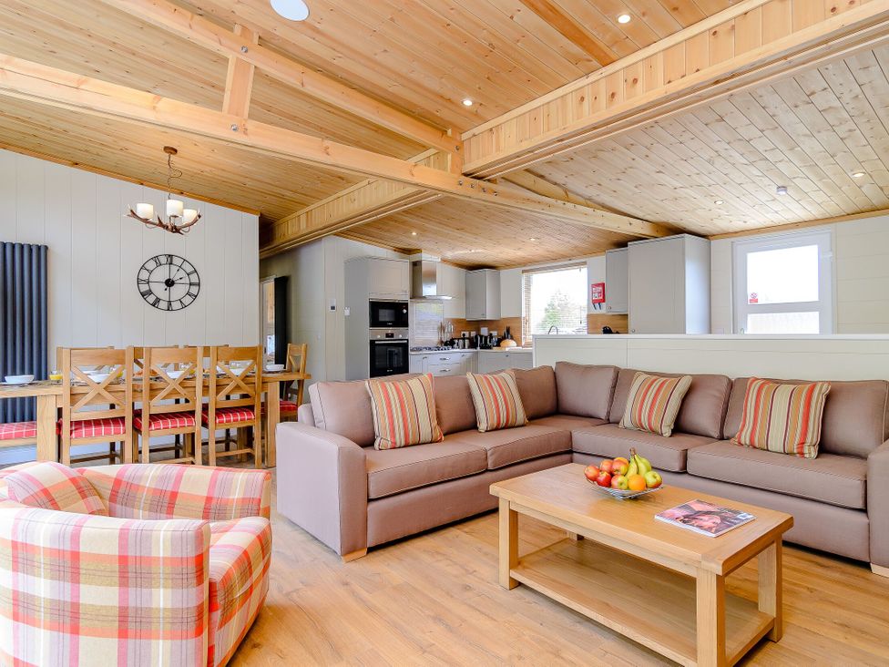 A living room with furniture and a kitchen area at The Fotheringhay in Kings Cliffe