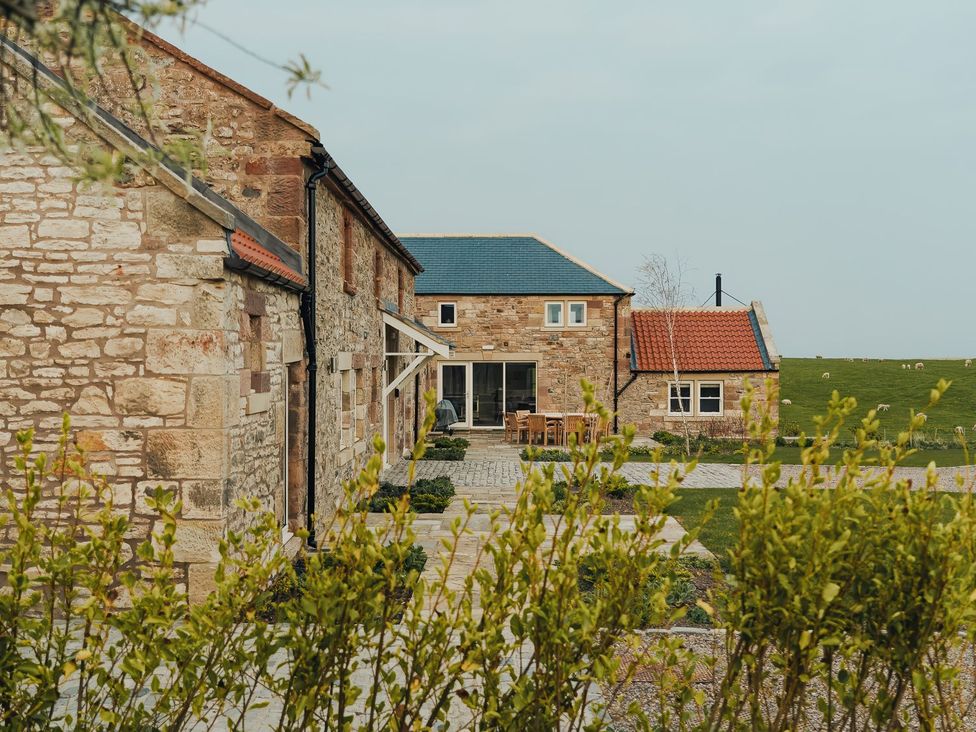 An outdoor area with stone buildings and patio furniture at The Old Watermill in Beadnell