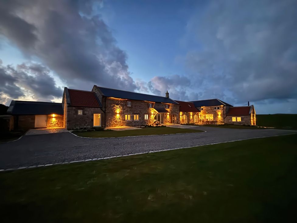 An exterior view of a stone building with lights at The Old Watermill in Beadnell