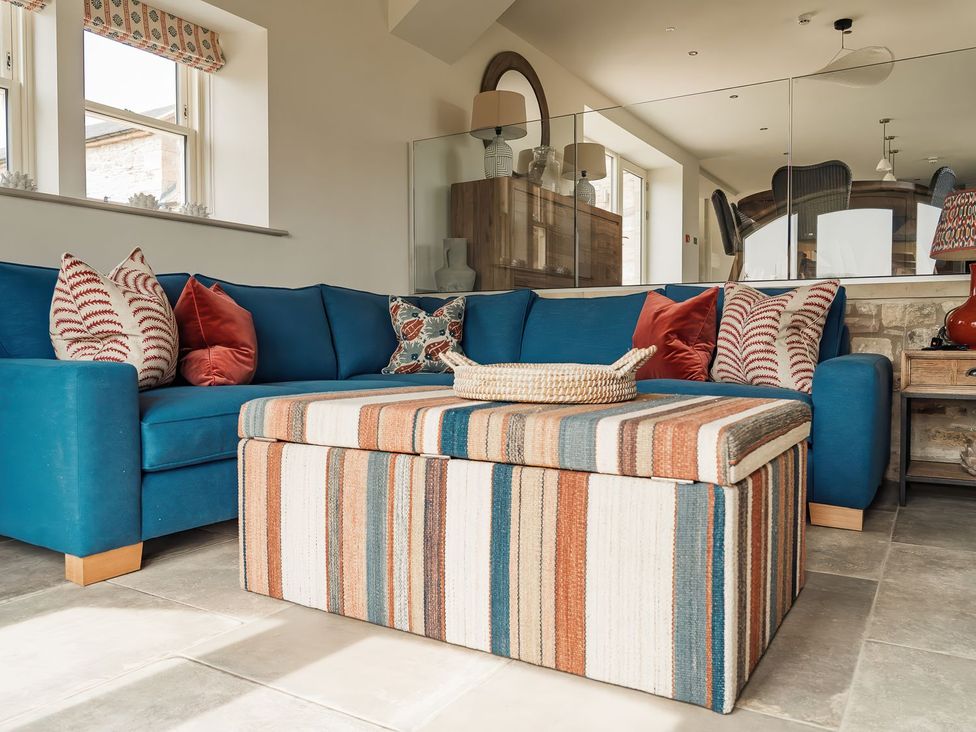 A living room with a blue sofa and striped ottoman at The Old Watermill in Beadnell