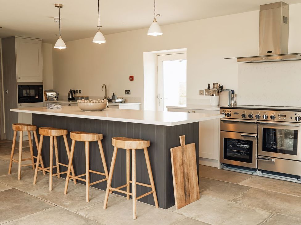 A kitchen with a kitchen island and bar stools at The Old Watermill in Beadnell