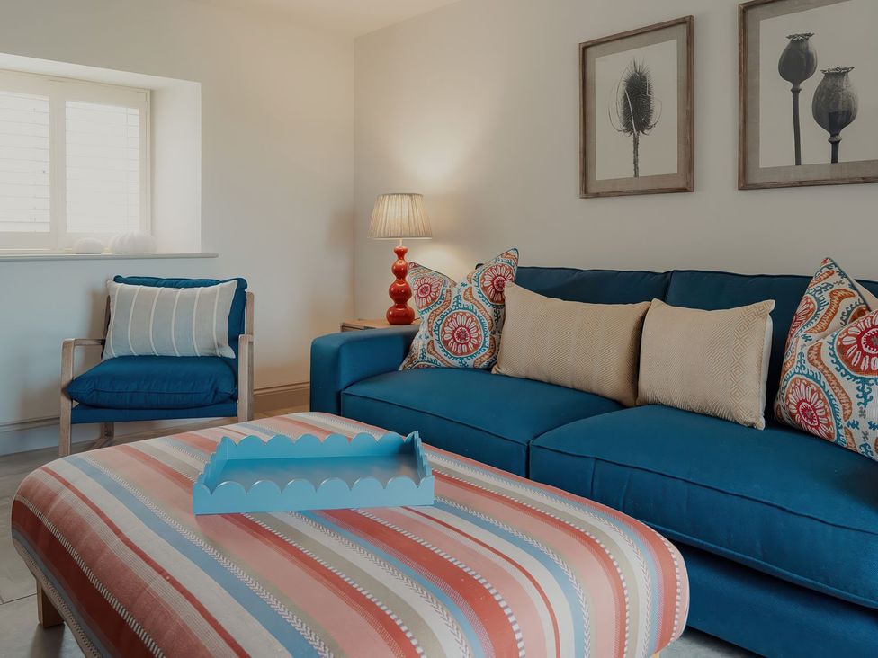 A living room with a blue sofa and decorative cushions at The Old Watermill in Beadnell
