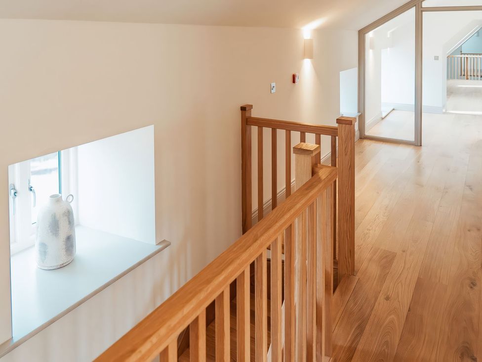 A hallway with a railing and a vase on a windowsill at The Old Watermill in Beadnell