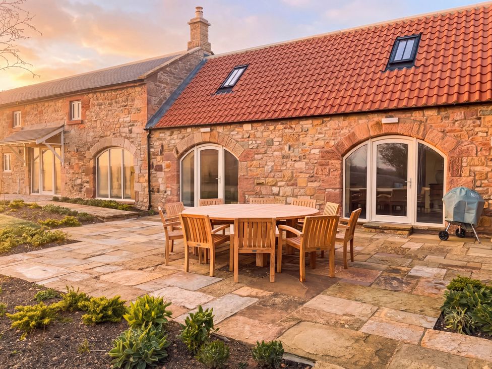 A patio with a wooden table and chairs at The Old Watermill in Beadnell