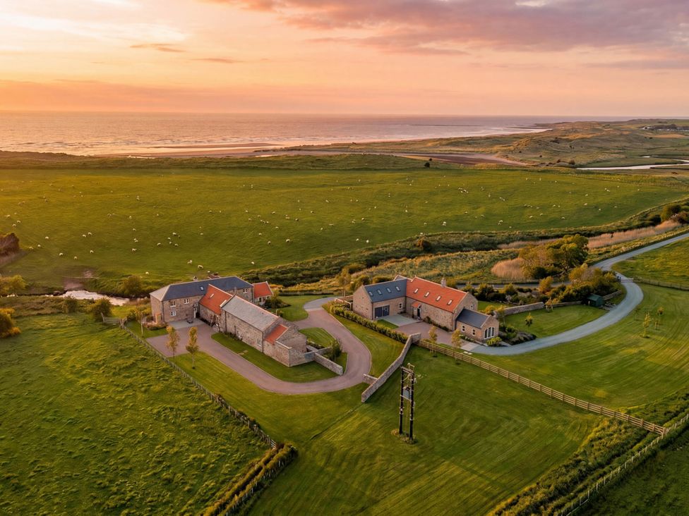 An aerial view of fields and houses near the ocean at The Old Watermill in Beadnell