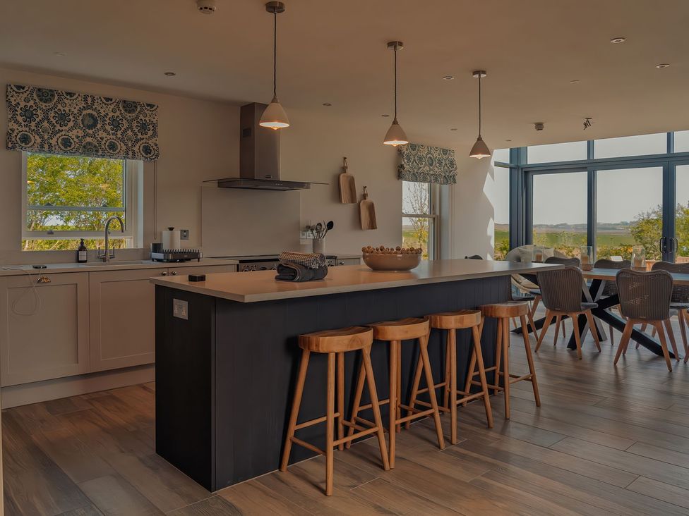 A kitchen with an island and bar stools at Mill Farm House Beadnell