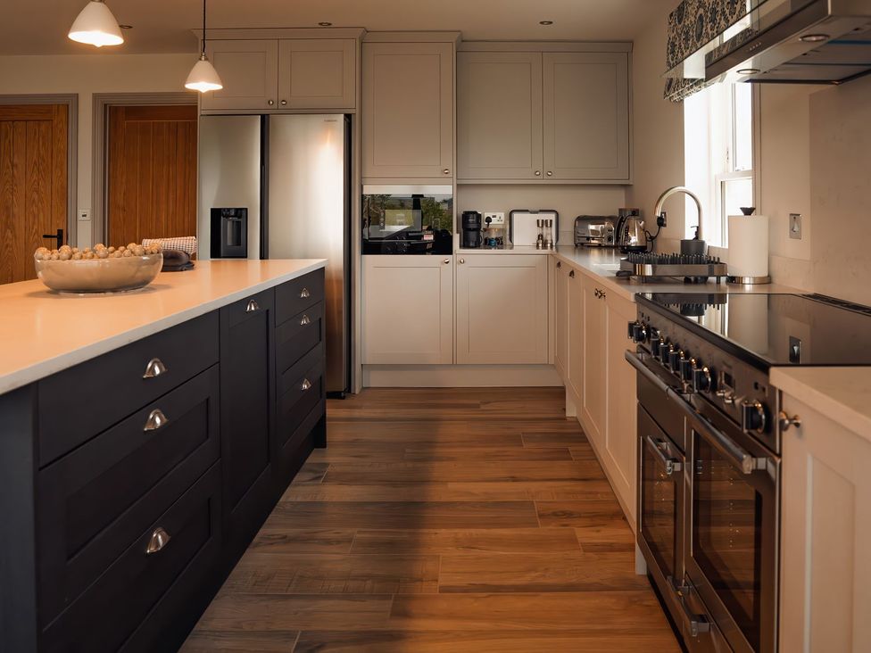 A kitchen with a countertop, refrigerator, and stove at Mill Farm House in Beadnell