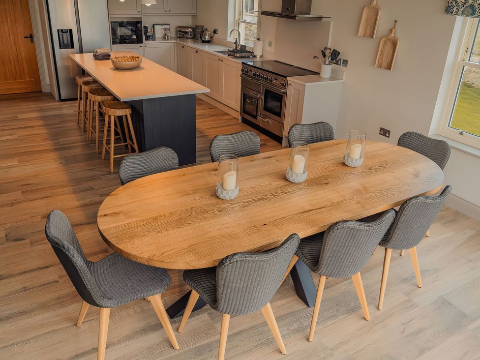 A dining room with a wooden table and chairs at Mill Farm House Beadnell