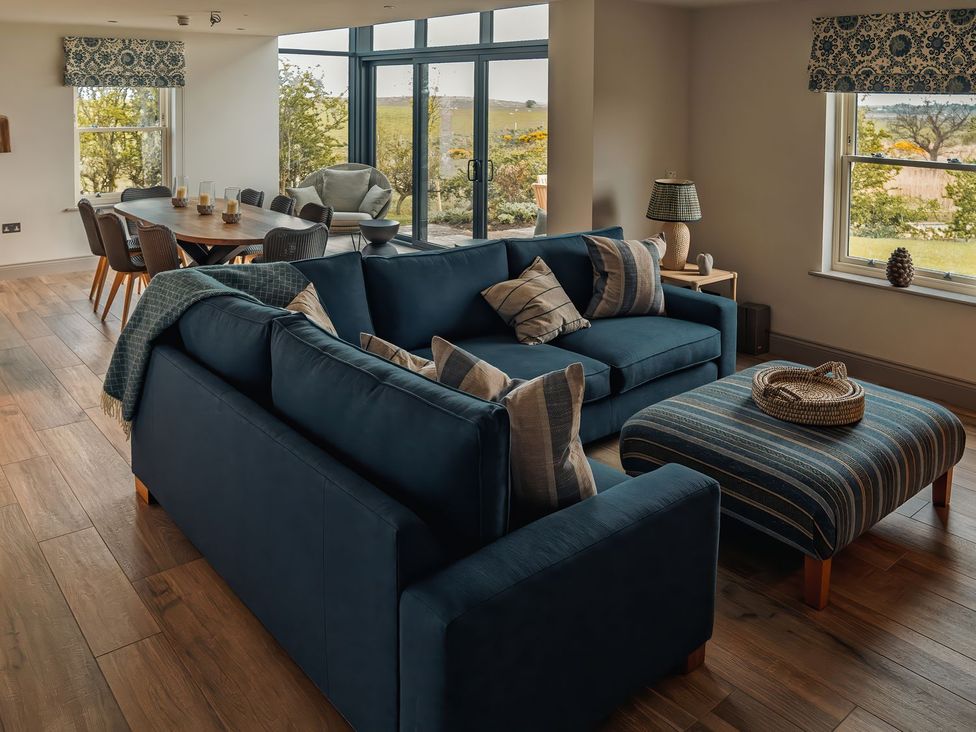A living room with a sofa and dining area at Mill Farm House in Beadnell
