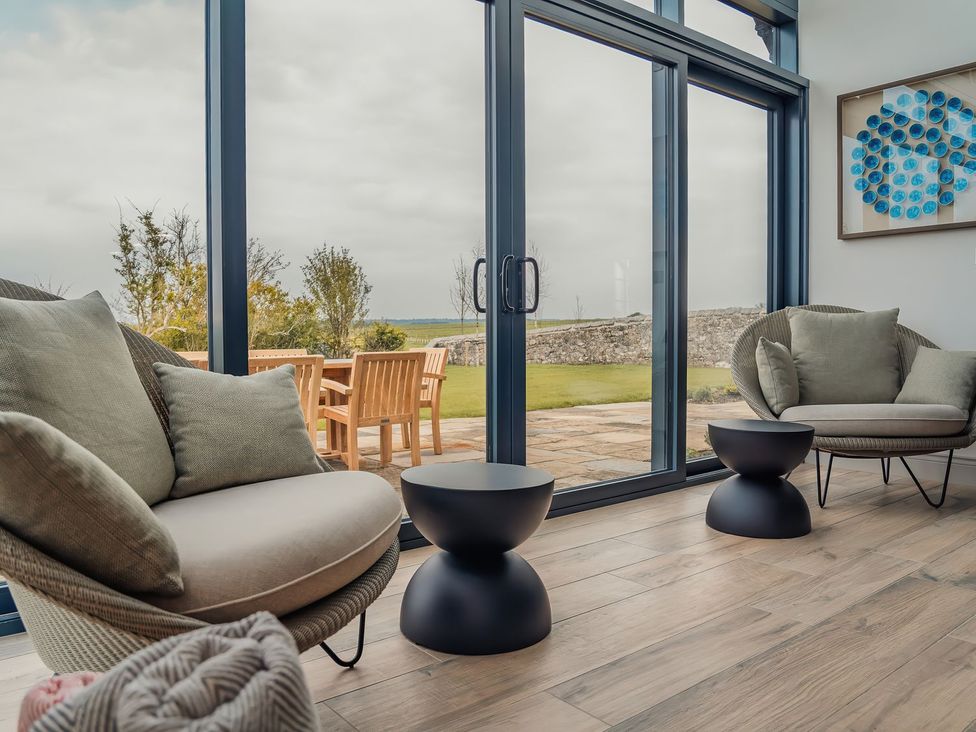 A conservatory with armchairs and a table at Mill Farm House Beadnell