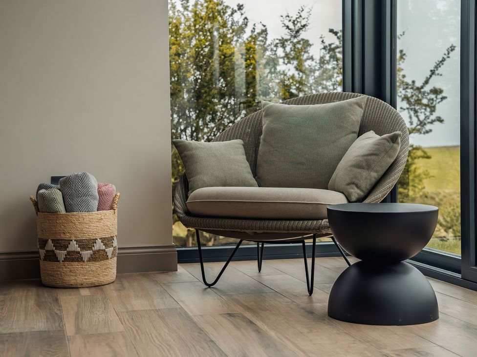 A snug with an armchair and a basket of throws at Mill Farm House Beadnell