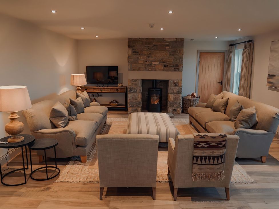 A living room with sofas and a fireplace at Mill Farm House in Beadnell