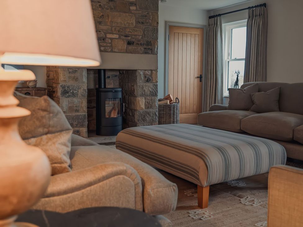 A living room with a fireplace and seating area at Mill Farm House Beadnell