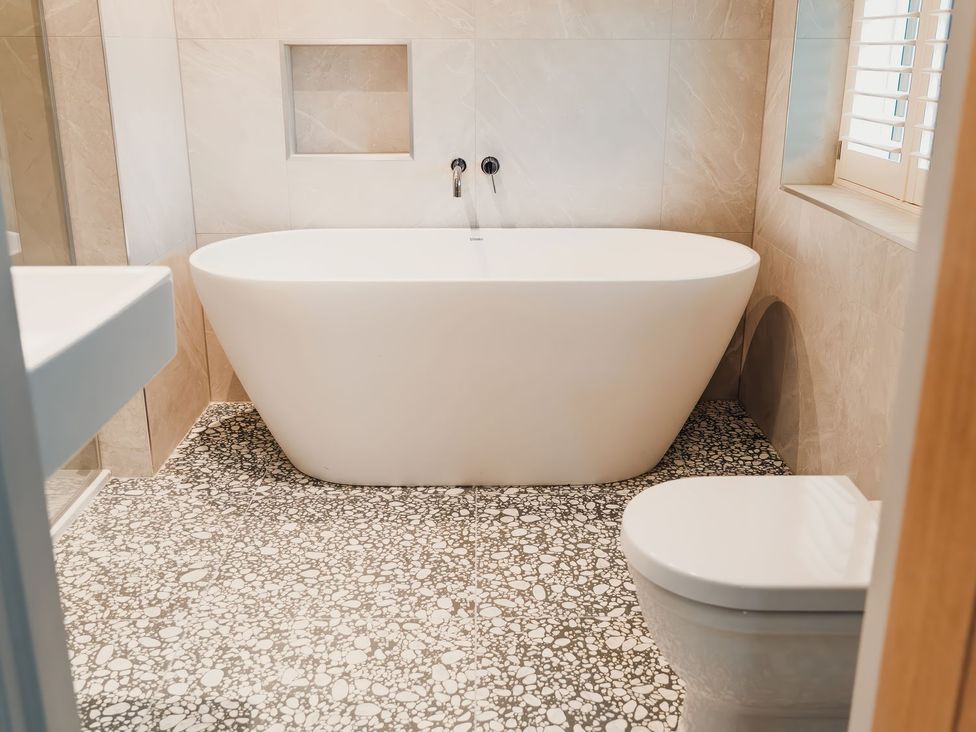A bathroom with a bathtub, toilet and sink at Mill Farm House in Beadnell