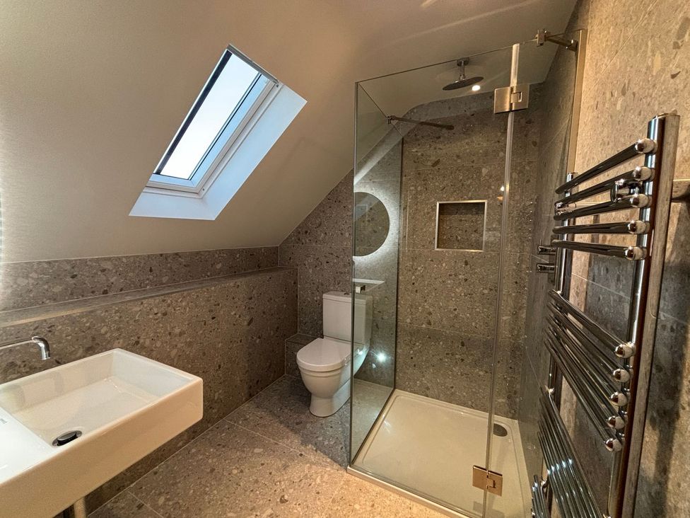 A bathroom with a shower, toilet, and sink at Mill Farm House Beadnell
