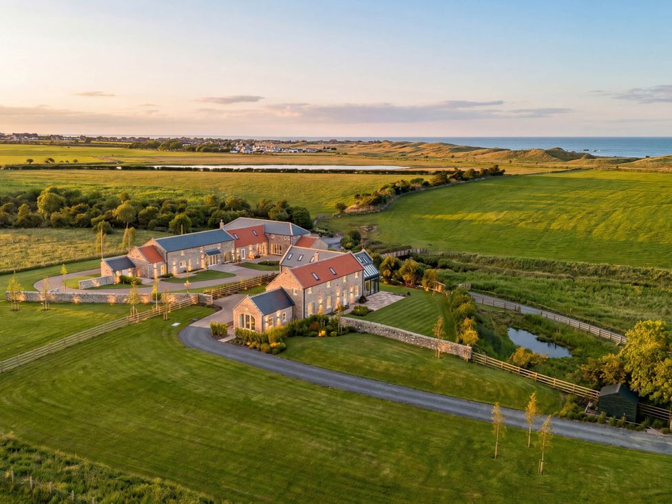 An aerial view of a property with a garden and pond at Mill Farm House in Beadnell