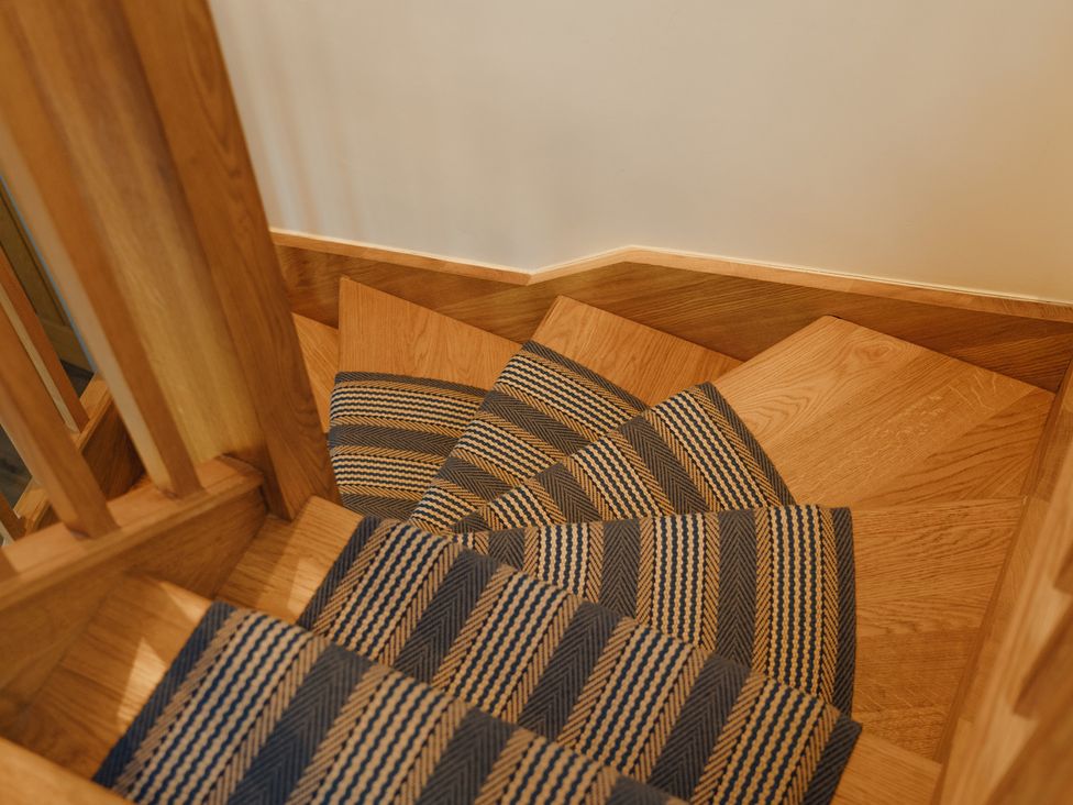 A staircase with wooden steps and a rug at Mill Farm House Beadnell