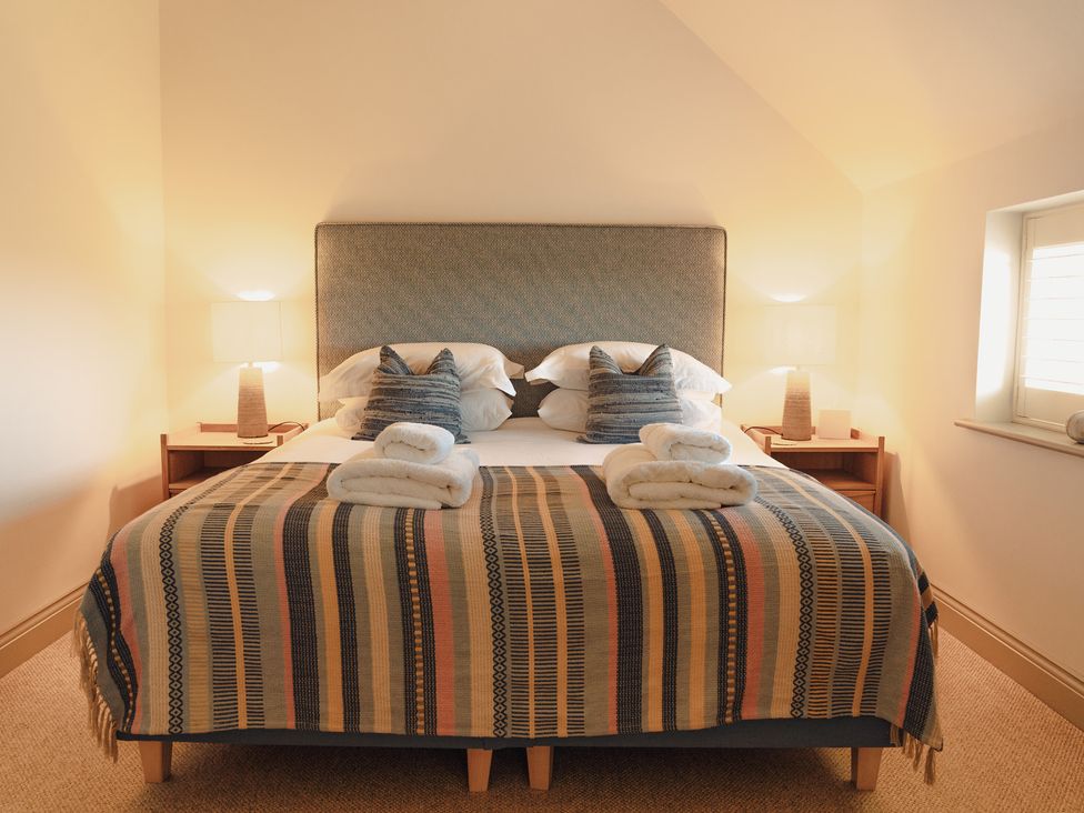 A bedroom with a bed and nightstands at Mill Farm House Beadnell