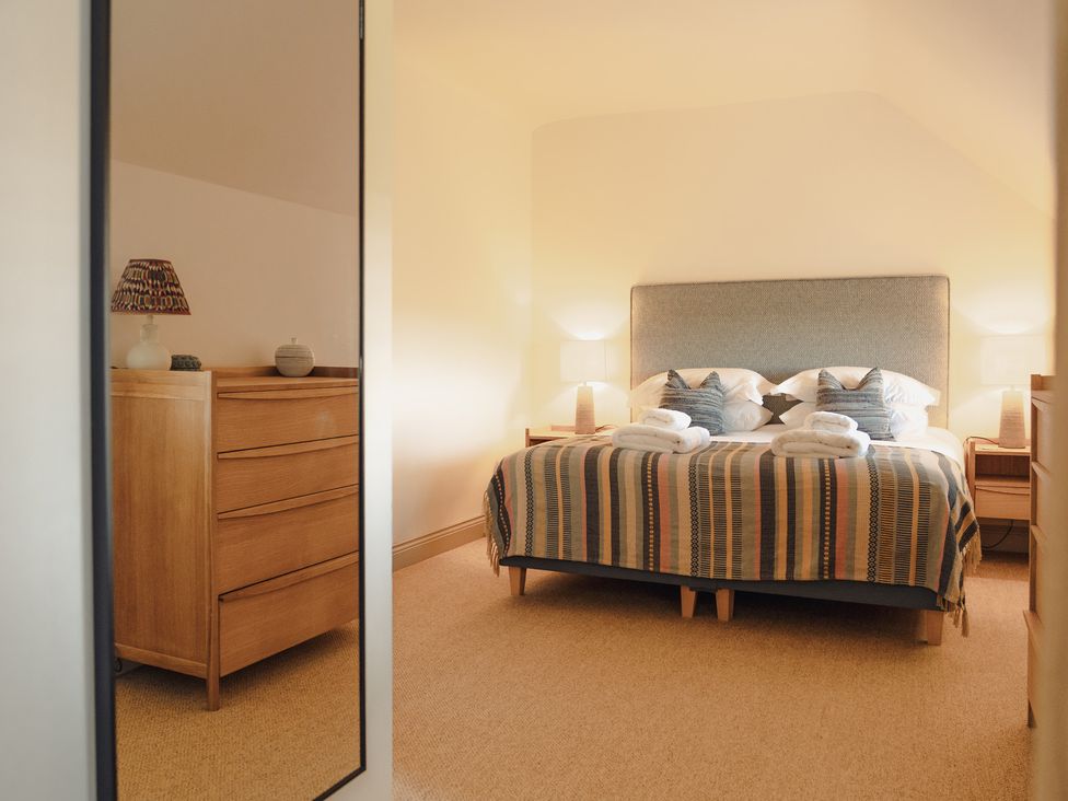 A bedroom with a large bed and dresser at Mill Farm House Beadnell