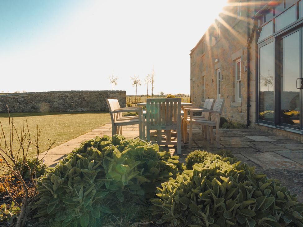A garden with a table and chairs at Mill Farm House in Beadnell