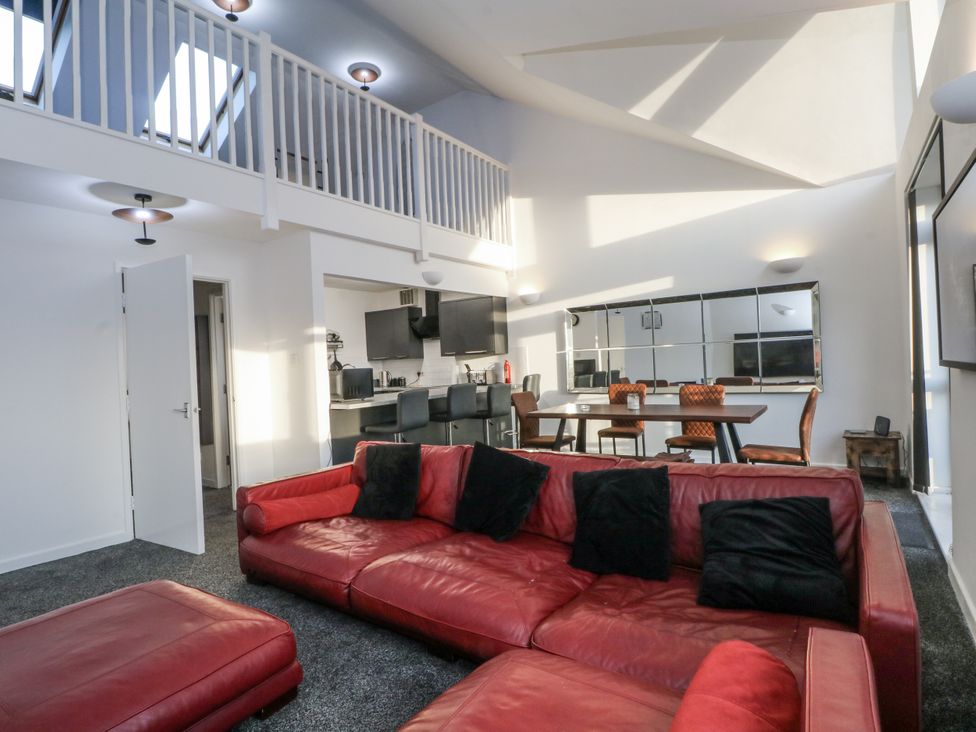 A living room with a red sofa and dining area at Manchester apartment in Manchester