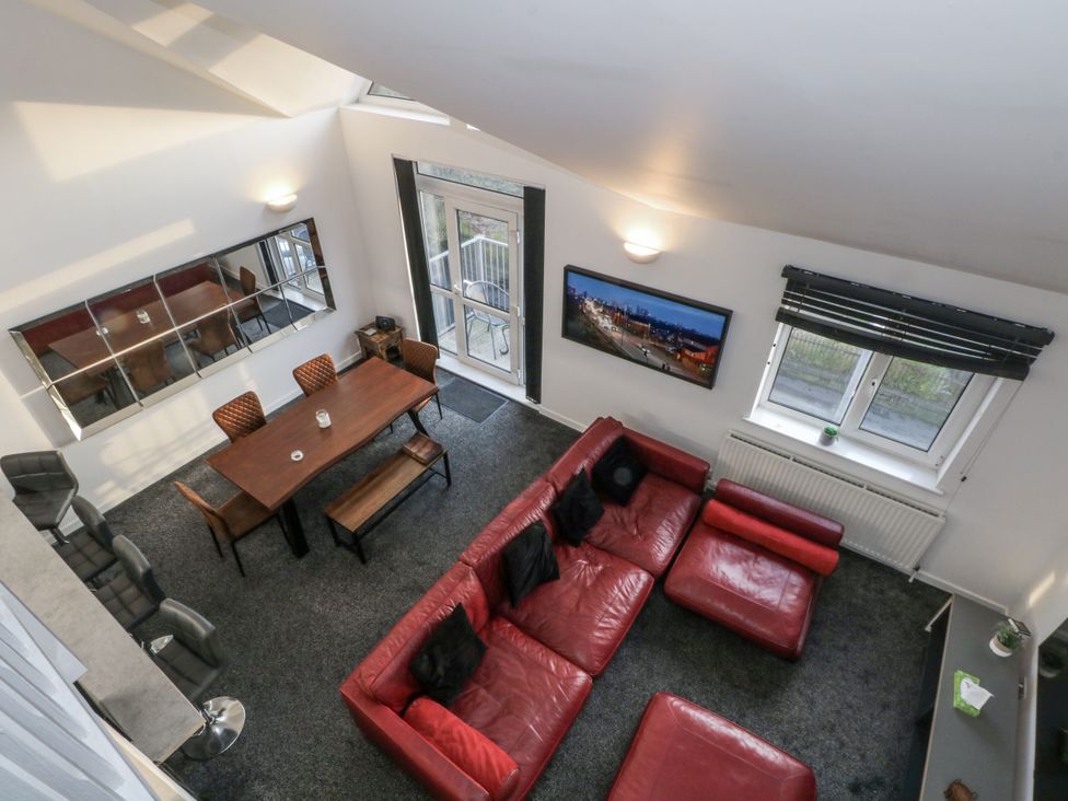 A living room with a dining table and red sofa at Manchester apartment in Manchester