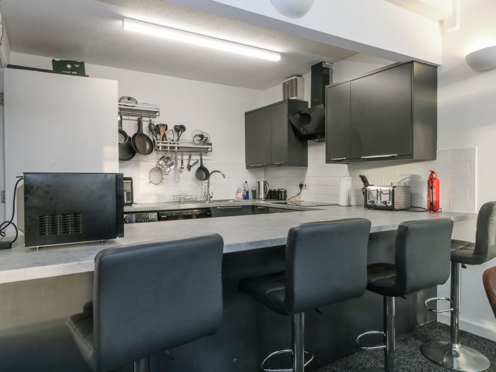 A kitchen with countertops and bar stools at Manchester apartment in Manchester