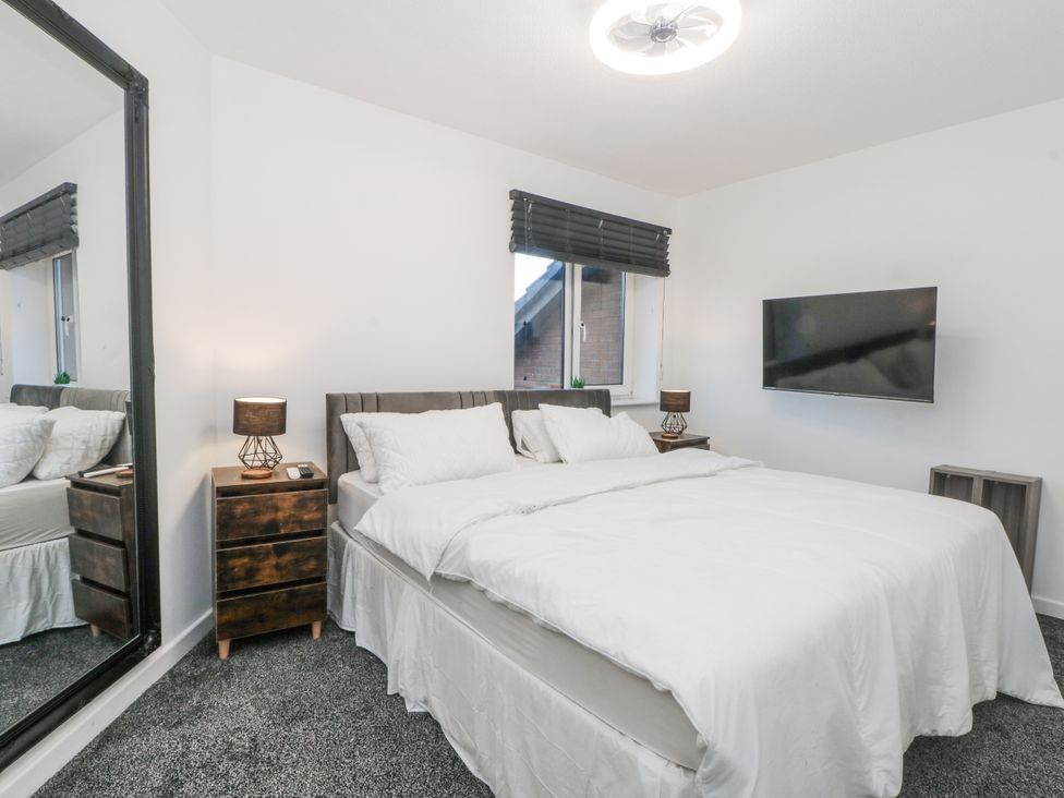 A bedroom with a bed and a television mounted on the wall at Manchester apartment in Manchester