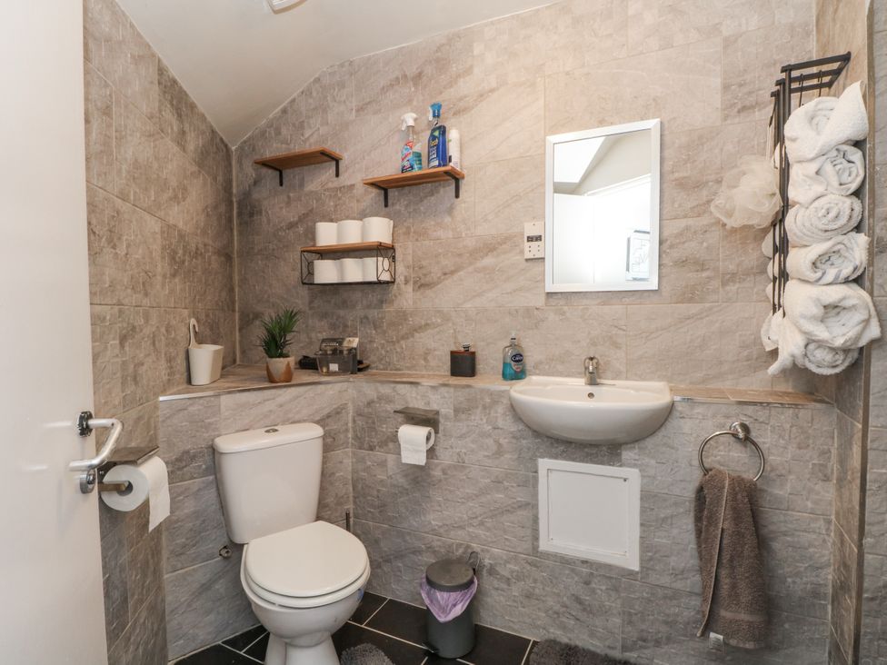 A bathroom with a toilet, sink, and shelves at Manchester apartment in Manchester