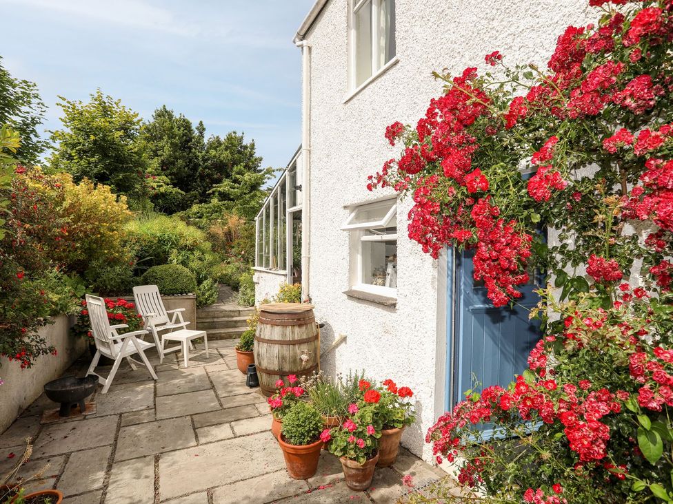 A garden with flowers and chairs at Bryn Tegid in Beaumaris