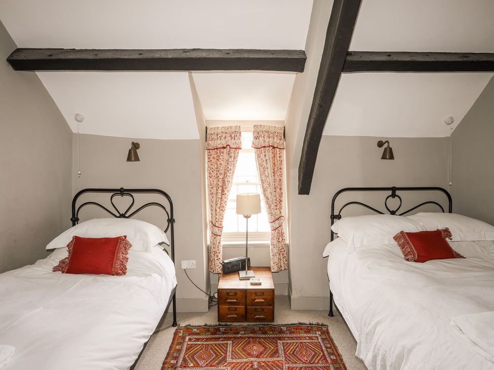 A bedroom with two beds and a side table at Bryn Tegid Beaumaris