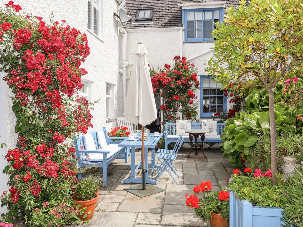 A garden with a table and chairs surrounded by flowers at Bryn Tegid in Beaumaris