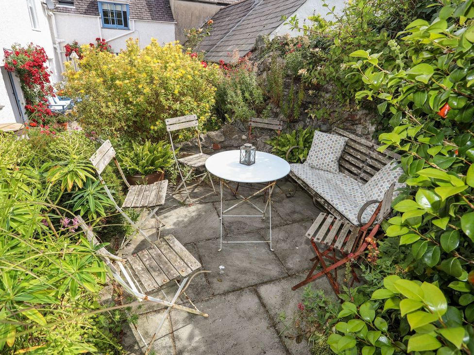 A garden with a table and chairs surrounded by plants at Bryn Tegid in Beaumaris