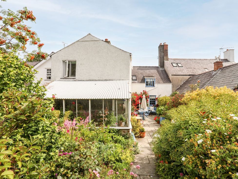 A garden with a greenhouse and flower beds at Bryn Tegid in Beaumaris