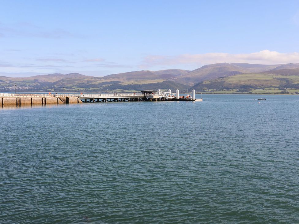 A pier extending into water with mountains in the background at Bryn Tegid Beaumaris